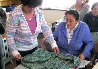 Muintir an Oileáin g cur taispeáintas ar fáil do na gascúir scoile seaicéad lámhdhéanta ag mná an oileáin